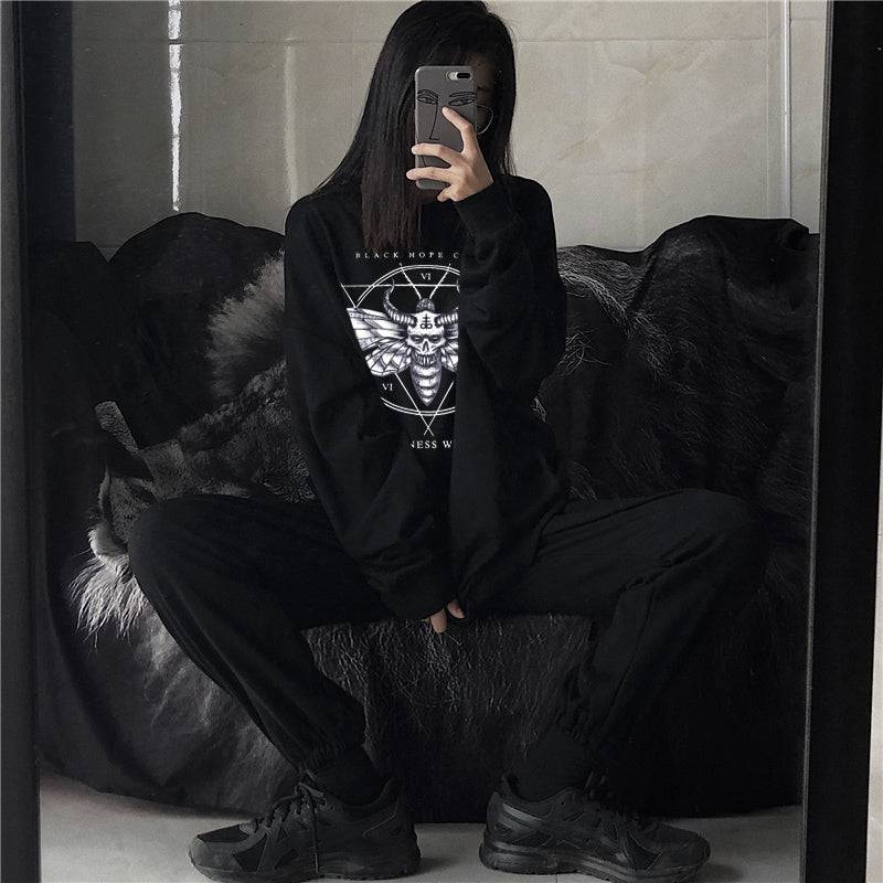 Women's oversized black hoodie with gothic graphic design, styled with black joggers and sneakers for a casual streetwear look.